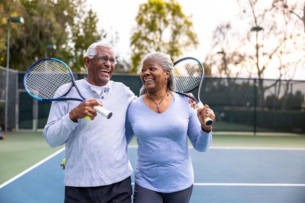 Active seniors happily playing tennis, managing knee osteoarthritis with a smile.