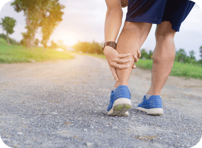 A person experiencing calf pain while running on a gravel path in Austin.