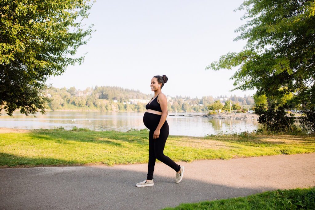 A mixed race young woman enjoys an exercise walk during the final weeks of her pregnancy, enjoying the summer sun and fresh air. A healthy active lifestyle for her and her unborn baby.