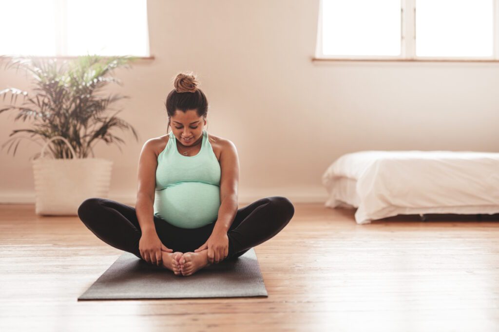 Beautiful expectant mother doing yoga at home