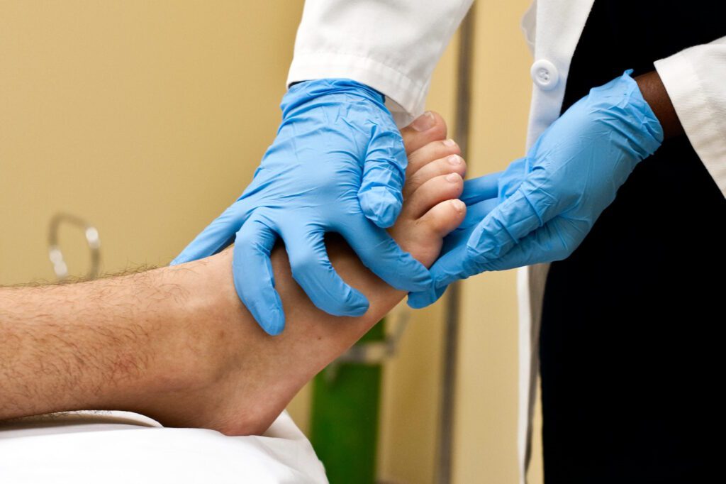 A medical professional checking a patient's toes.