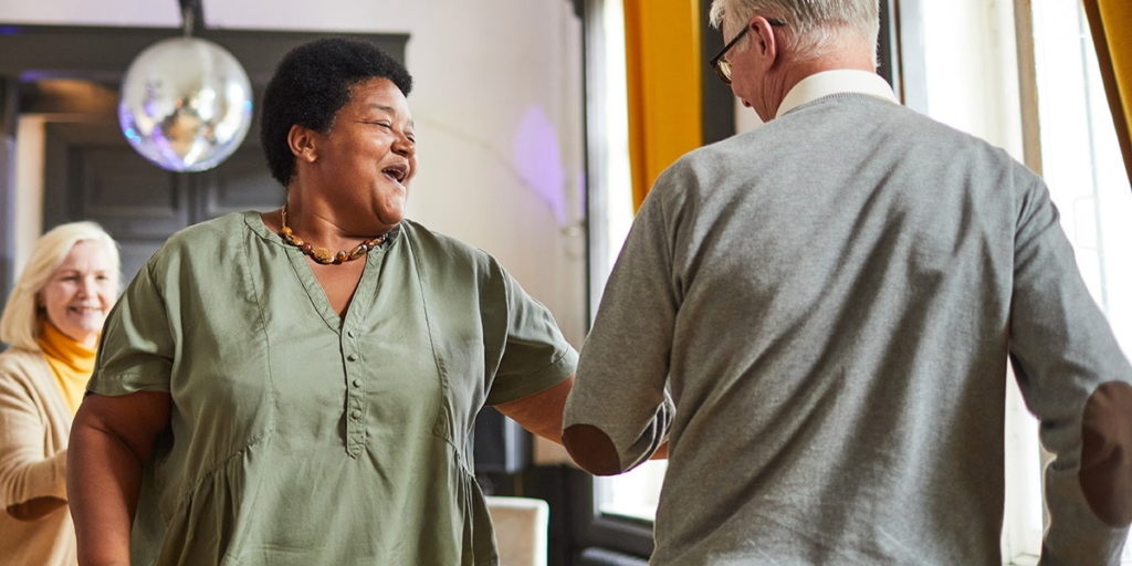 An elderly woman and an elderly man are smiling at each other, enjoying their time together in a happy and cheerful mood.