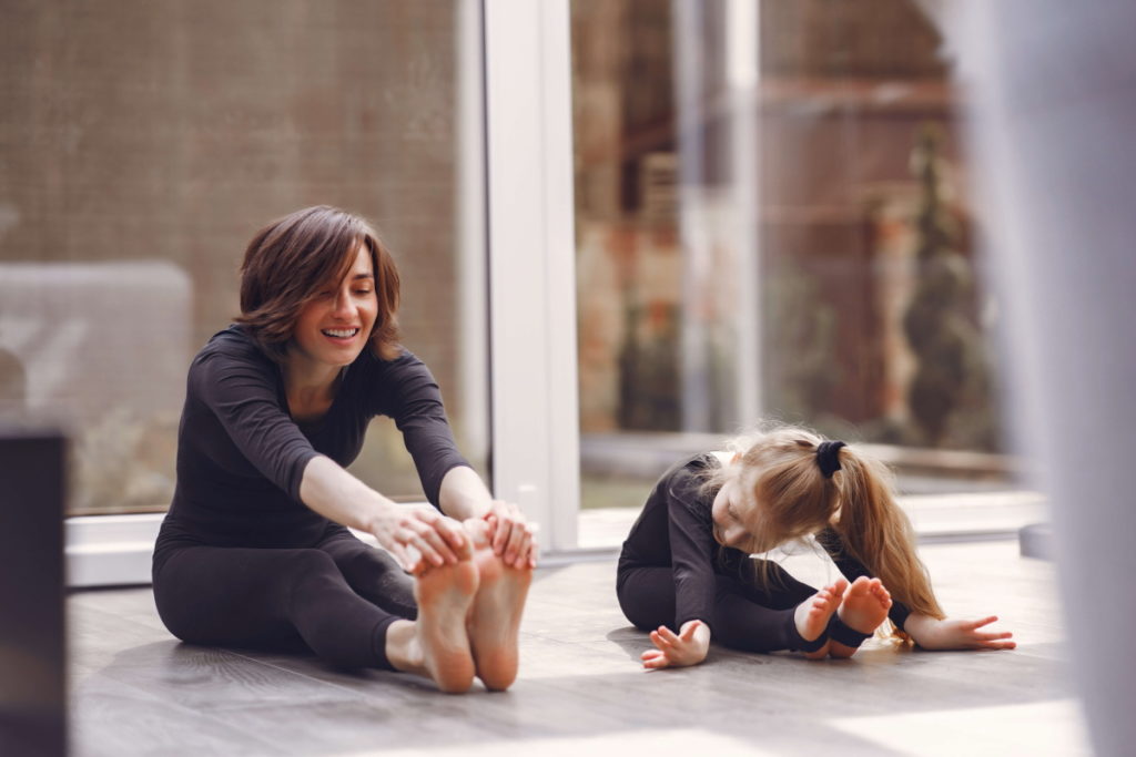 A beautiful woman is exercising with her little baby.