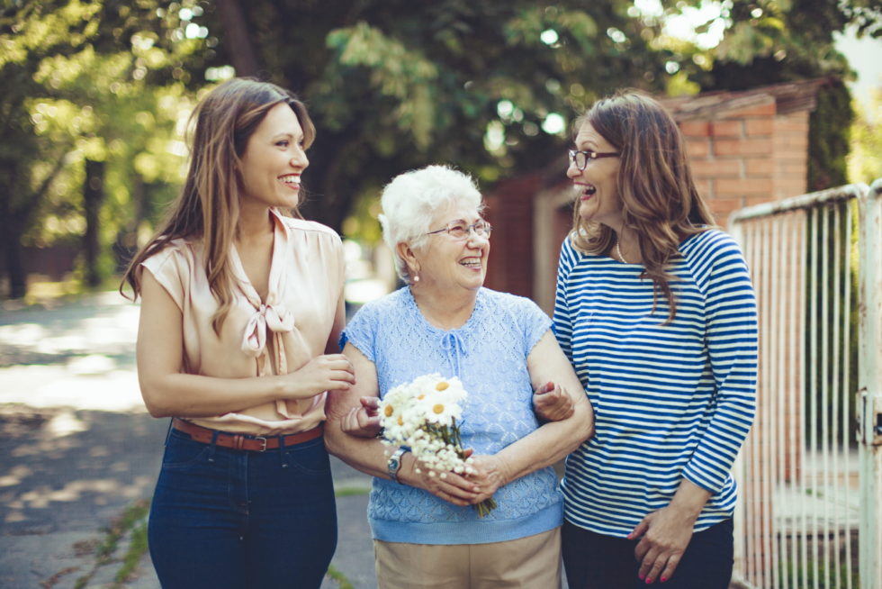 Two young girls are holding the hands of an elderly woman