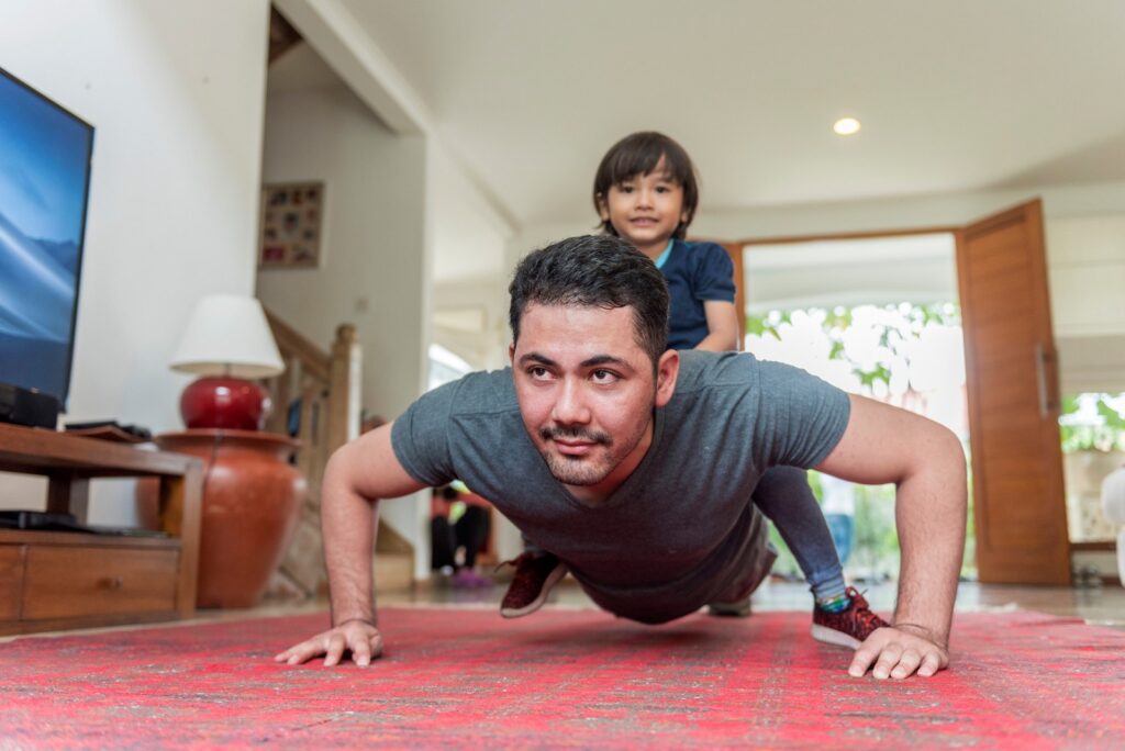 Father and son doing push up on a living room