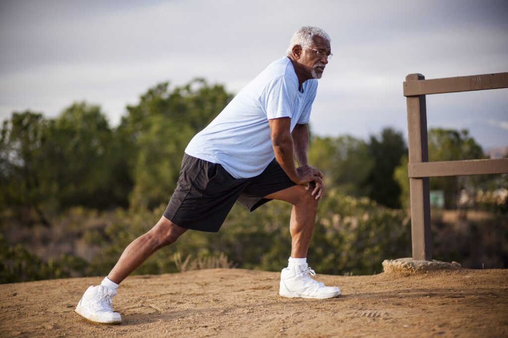 An attractive senior black man exercises outdoors with various muscle stretches