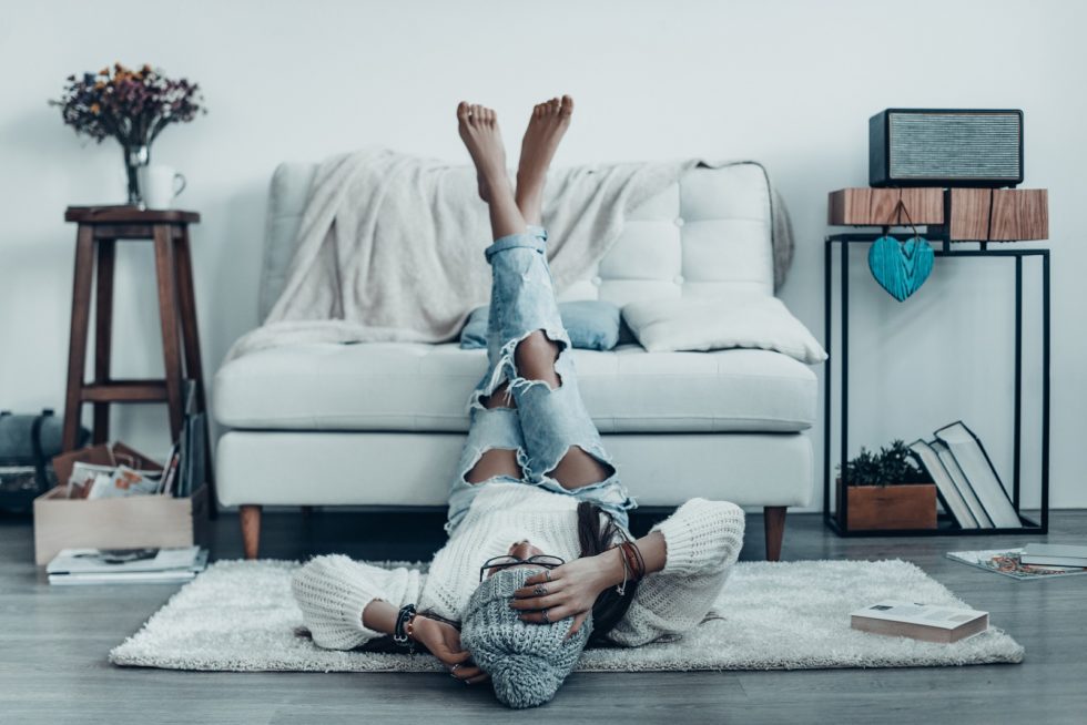 Beautiful young woman in casual wear touching her head with hand while lying on the floor at home