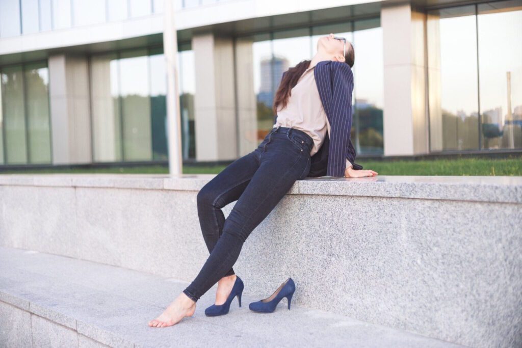 A woman wearing high heels takes a break to relax her aching feet.