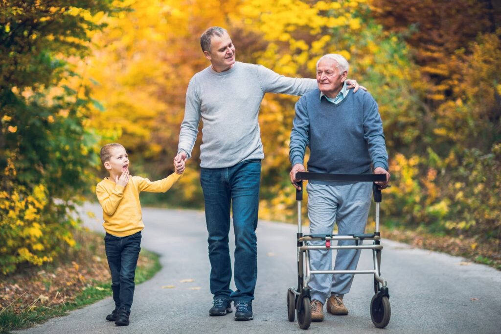 A child, a young man, and an elderly man are walking down the road holding hands.