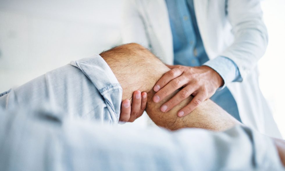 A doctor examines a patient's knee.