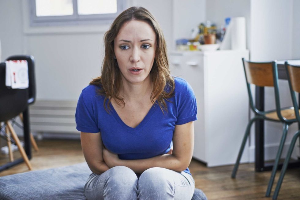 Seated girl gently holding her stomach