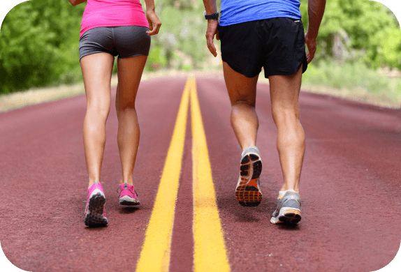 the lower bodies of two people running on a paved road