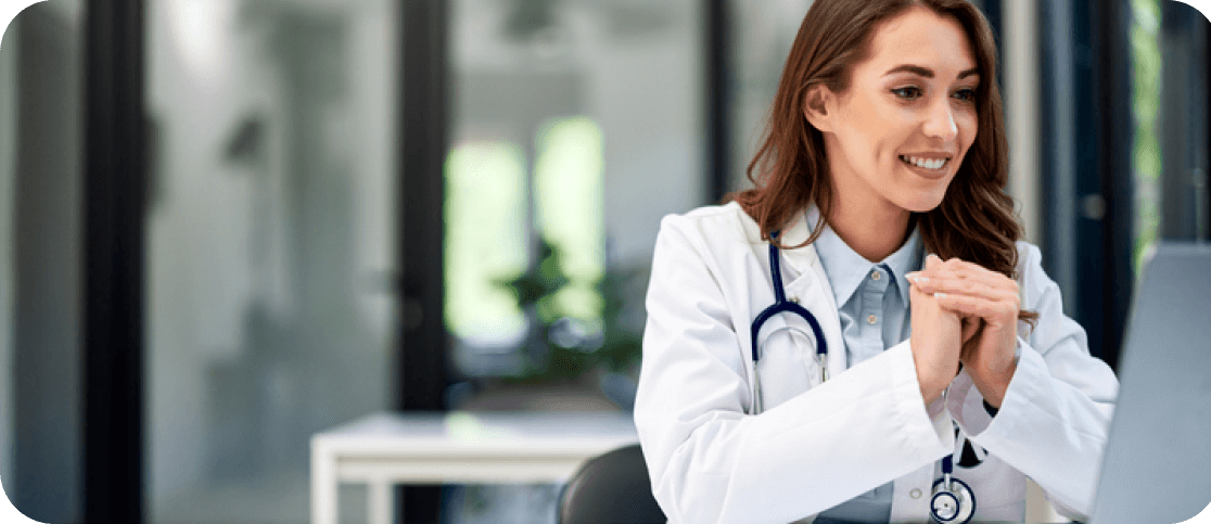 Happy doctor smiling while watching laptop screen